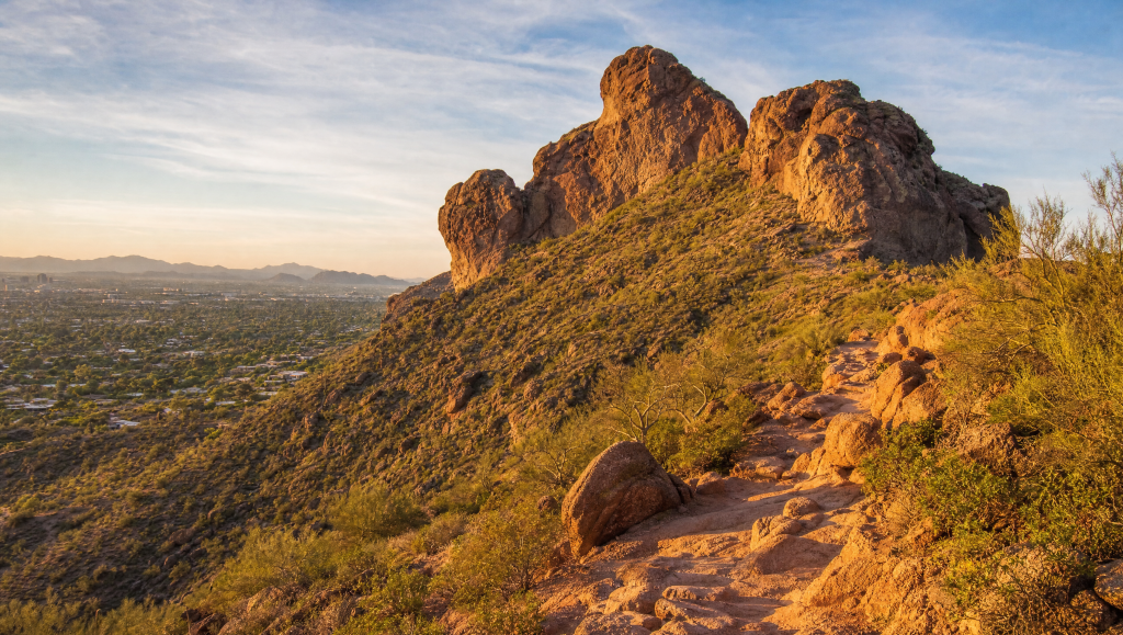 View of the rocky summit trail at Camelback Mountain surrounded by desert vegetation under a clear sky.
