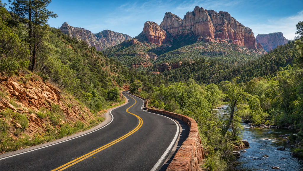 Winding paved road through the wooded valley and towering cliffs of Oak Creek Canyon in Sedona, Arizona.