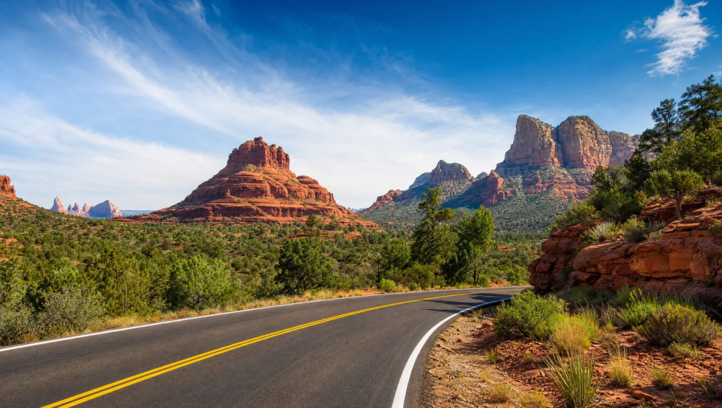Scenic view of State Route 179 winding through the red rock landscape and towering sandstone formations in Sedona, Arizona.